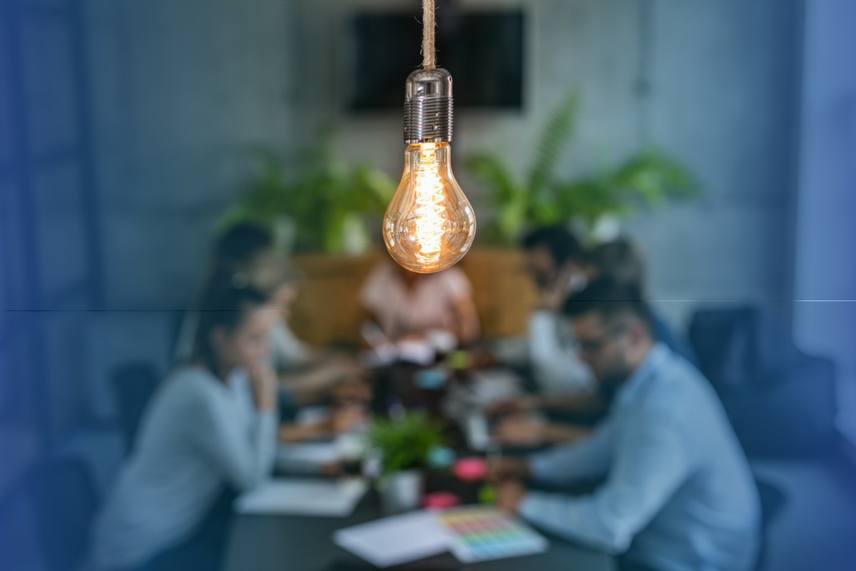 People working at a desk with a focus on a lightbulb