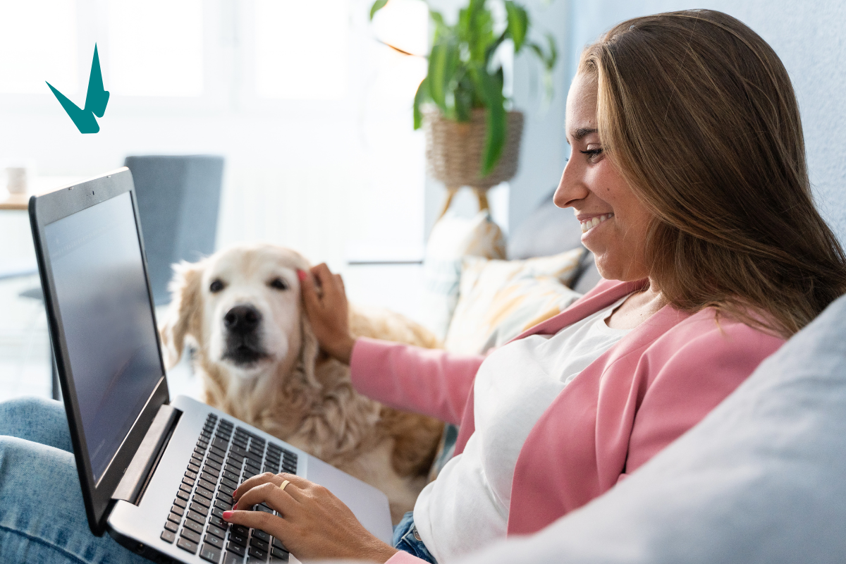 A female employee working on the computer from work while petting her cute dog.